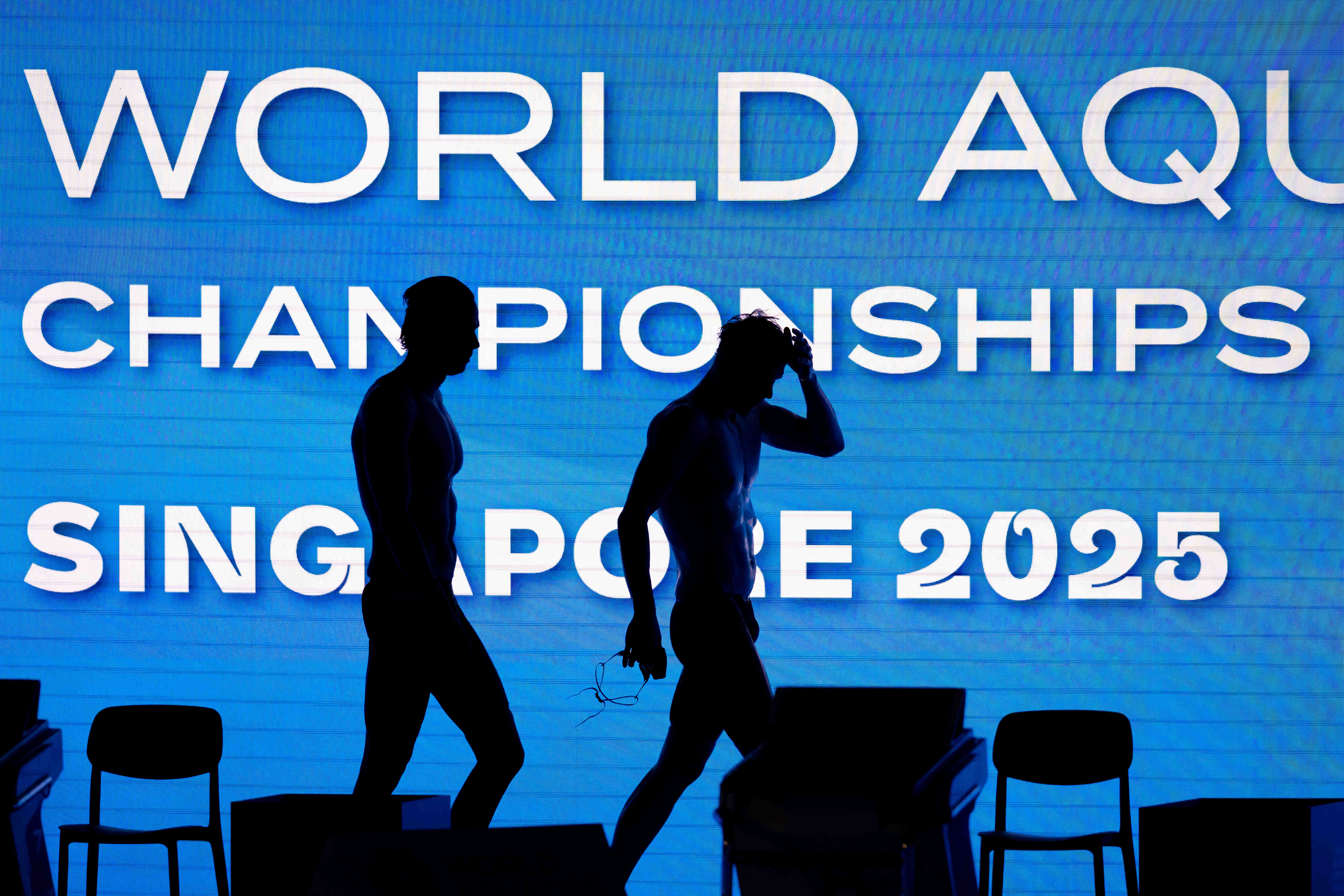 Two swimmers leaving the competition stage as silhouettes in Singapore