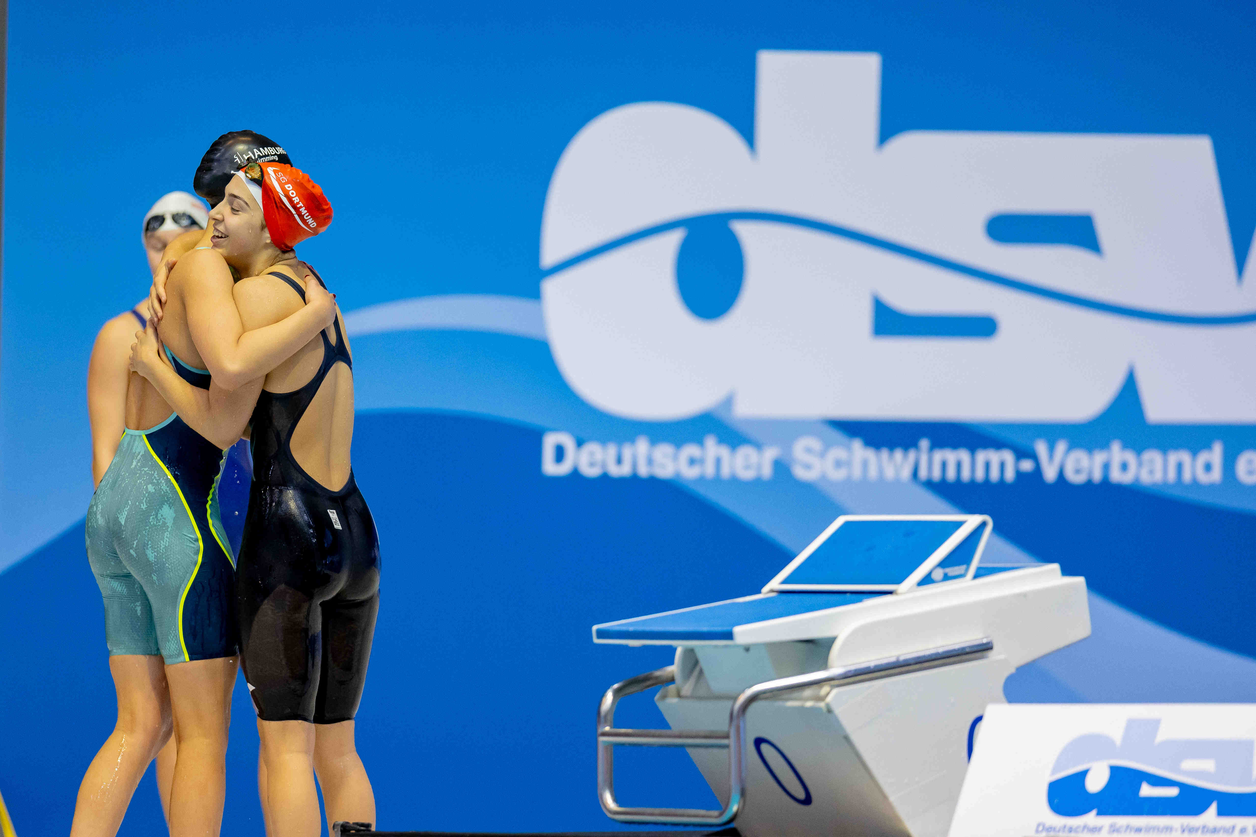 DJM athletes embracing in front of DSV logo